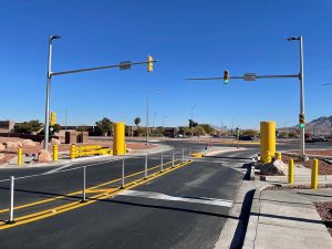 A road with yellow traffic barriers, signals, and clear skies in an urban area.