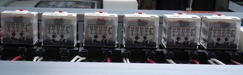 A row of six electrical relays labeled CR3 to CR7 connected with white and red wires.